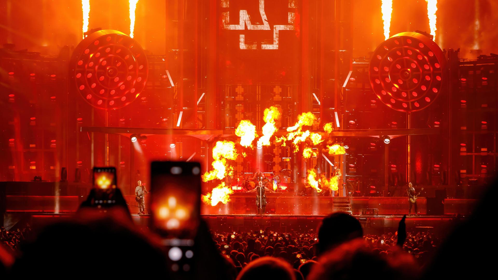 Konzert der Band Rammstein: Menschen im Publikum filmen mit dem Smartphone eine Feuershow auf der Bühne. 