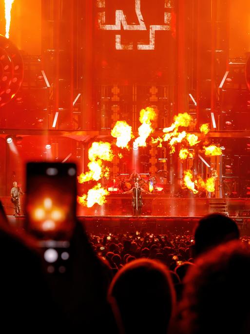 Konzert der Band Rammstein: Menschen im Publikum filmen mit dem Smartphone eine Feuershow auf der Bühne. 