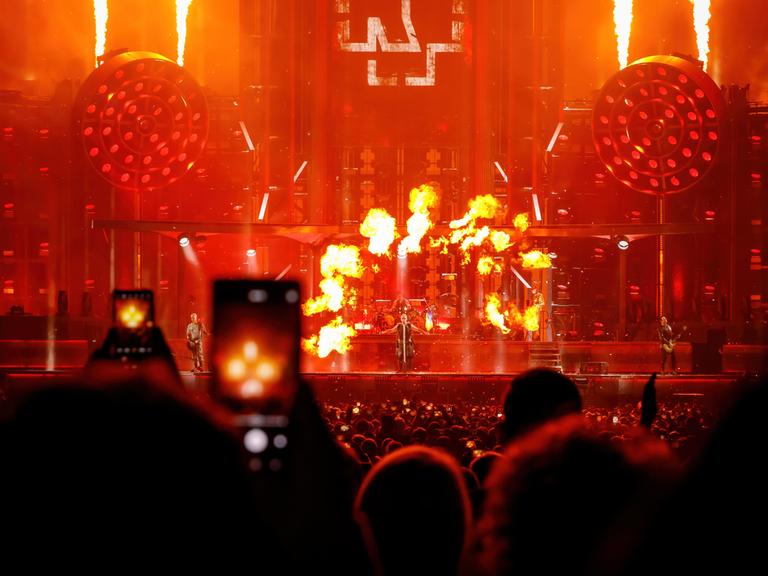 Konzert der Band Rammstein: Menschen im Publikum filmen mit dem Smartphone eine Feuershow auf der Bühne. 