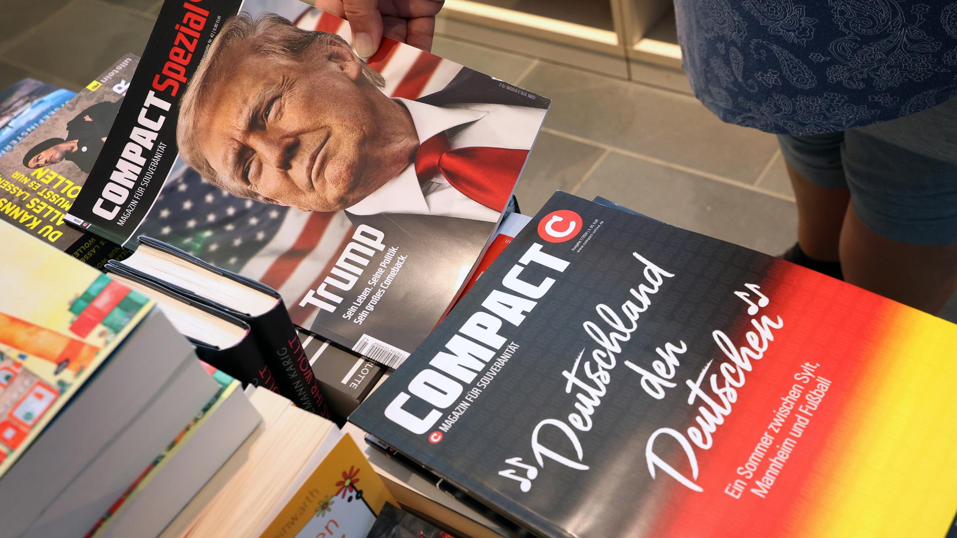 In einer Bahnhofsbuchhandlung sind liegen verschiedene Ausgaben des rechtsextremen Magazins "Compact" auf einen Stapel, auf einem davon ist der Titel "Deutschland den Deutschen" zu lesen. In einer Bahnhofsbuchhandlung sind liegen verschiedene Ausgaben des rechtsextremen Magazins "Compact" auf einen Stapel, auf einem davon ist der Titel "Deutschland den Deutschen" zu lesen.