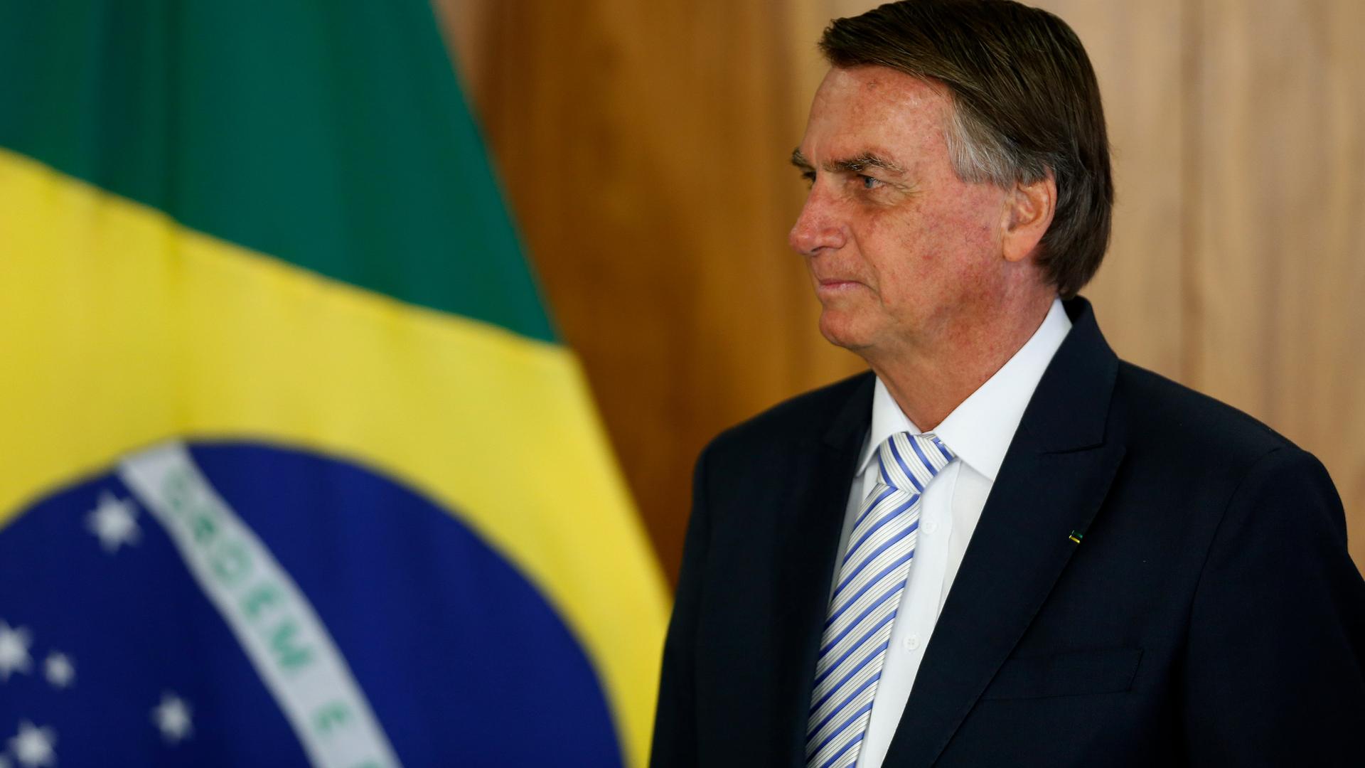 Brasiliens Präsident Jair Bolsonaro neben der brasilianischen Flagge