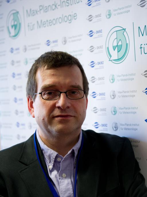 Jochem Marotzke steht vor einem Schild mit dem Schriftzug "Max-Planck-Institut für Meteorologie".