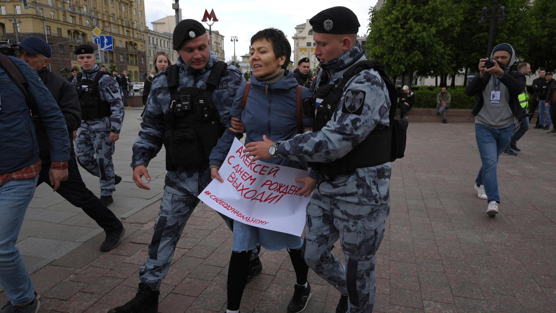 Polizisten führen eine Demonstrantin auf dem Puschkinskaja-Platz ab, die ein Plakat mit der Aufschrift "Happy Birthday Alexej" trägt.