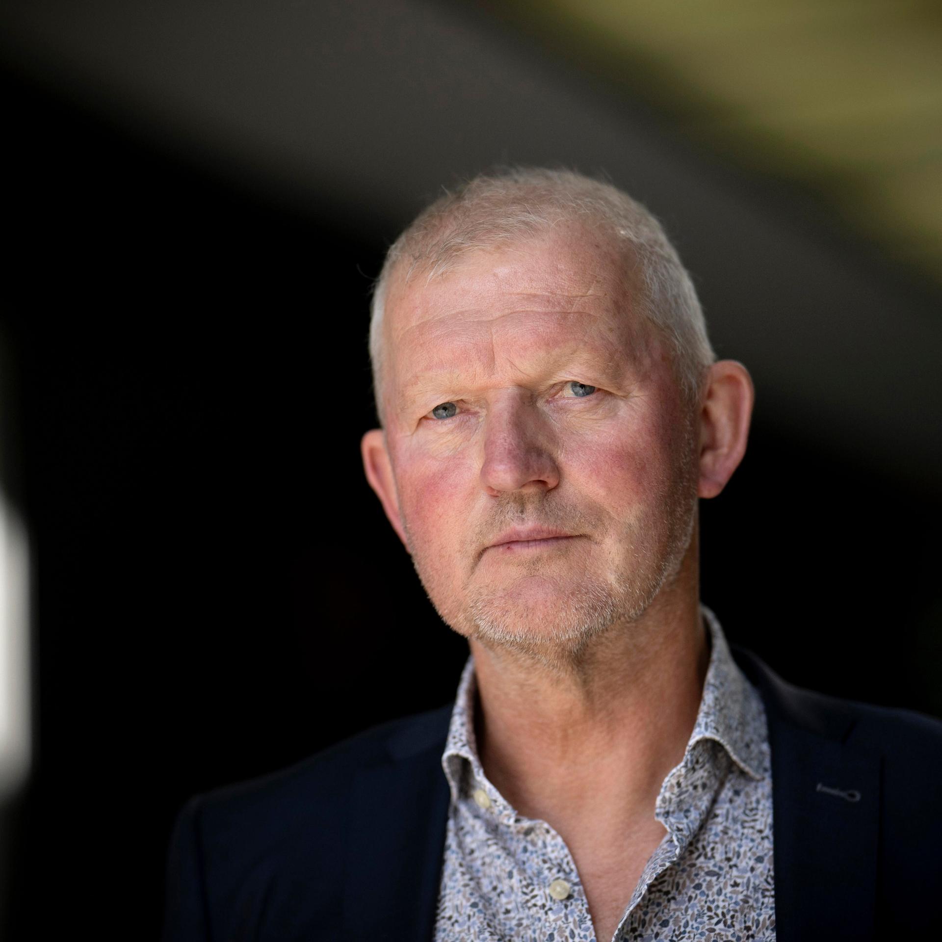 Das Foto zeigt Prof. Olaf Köller im Porträt. Er trägt ein gemustertes Hemd und eine dunkle Jacke darüber und blickt ernst in die Kamera. Der Hintergrund ist verschwommen.
