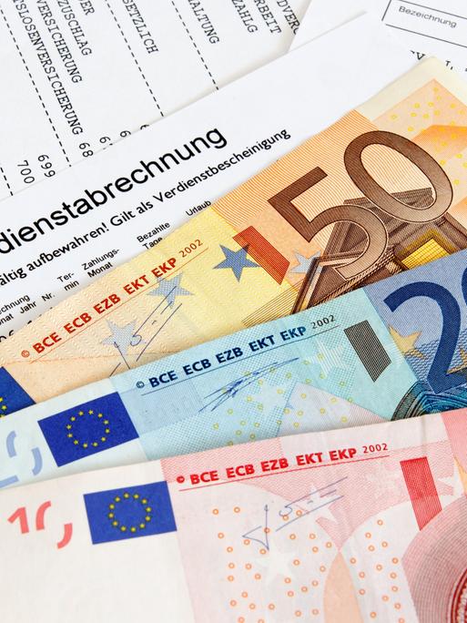 Gehaltszettel einer Person, darauf liegen Geldscheine (50-, 20- und 10-Euro-Schein)