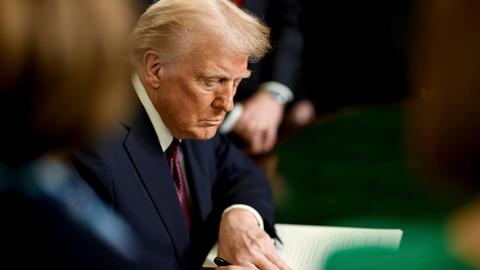 US-Präsident Donald Trump sitzt an einem Tisch und unterschreibt ein Dekret. 