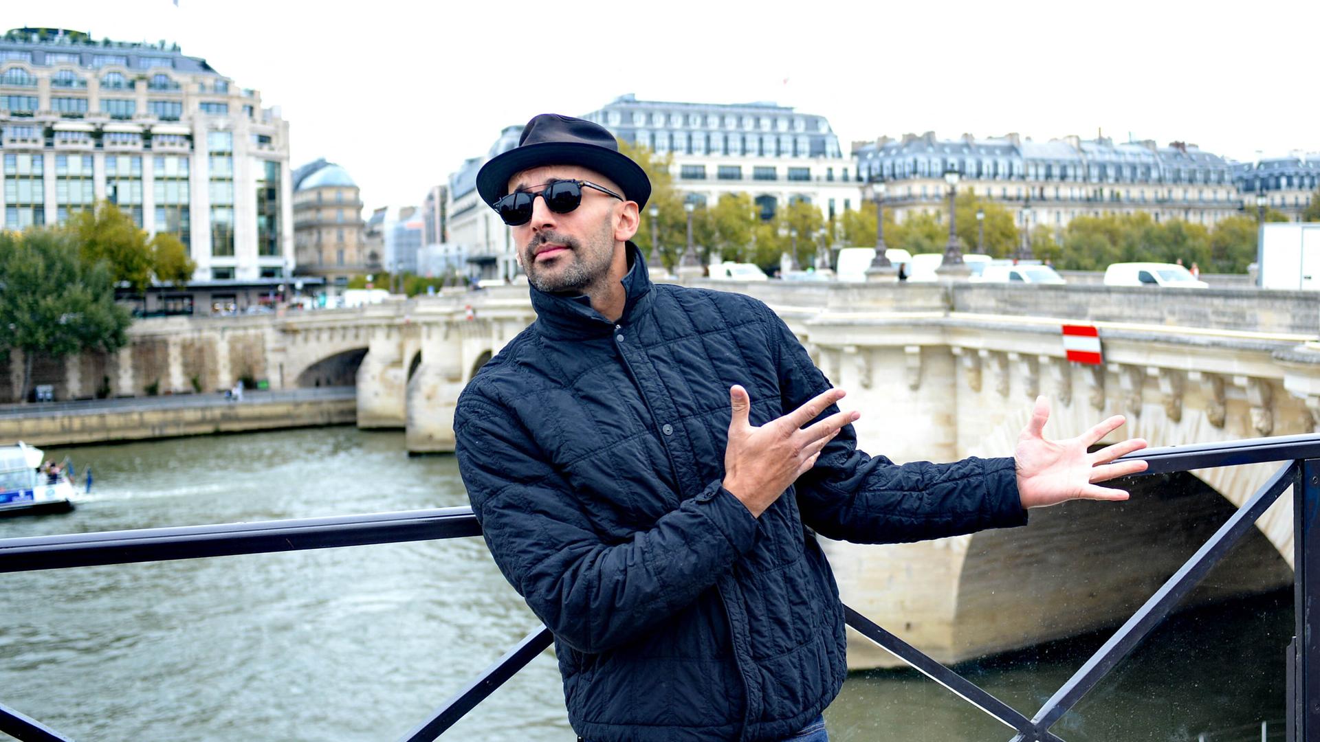 Der französische Künstler JR steht vor der Pariser Brücke Pont Neuf am Ufer der Seine.