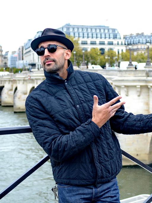 Der französische Künstler JR steht vor der Pariser Brücke Pont Neuf am Ufer der Seine.