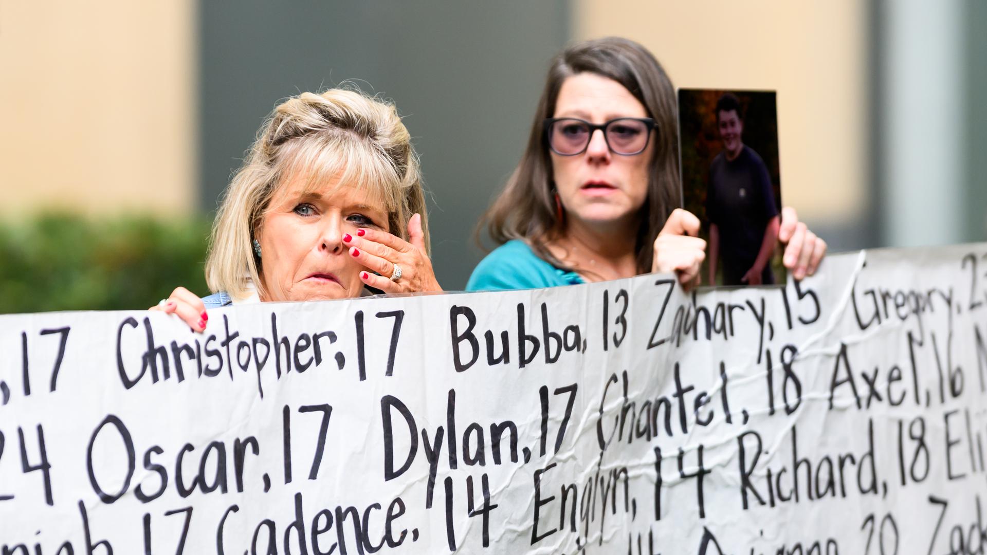 Eine Frau, deren Tochter im Alter von 18 Jahren starb, hält vor dem Gerichtsgebäude ein Transparent mit den Namen junger Menschen hoch, die laut Aktivisten infolge der Nutzung sozialer Medien ums Leben gekommen sind. Eine Frau, deren Tochter im Alter von 18 Jahren starb, hält vor dem Gerichtsgebäude ein Transparent mit den Namen junger Menschen hoch, die laut Aktivisten infolge der Nutzung sozialer Medien ums Leben gekommen sind.