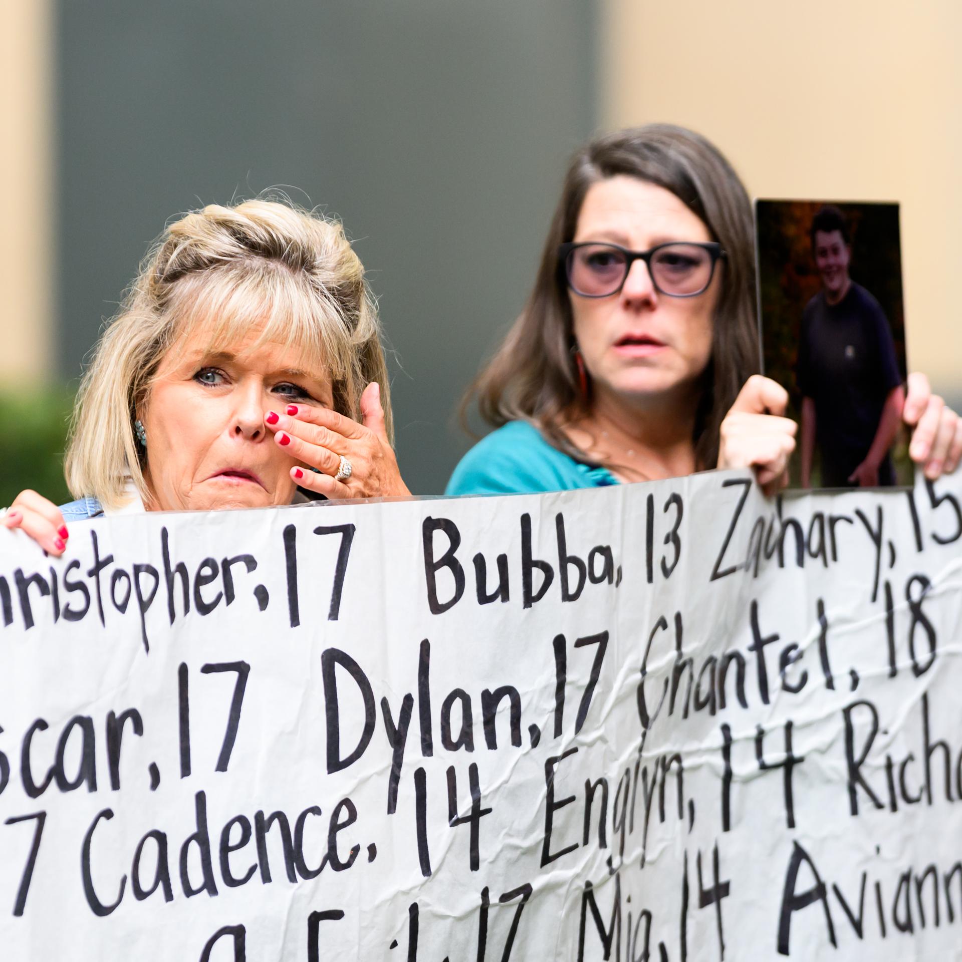 Eine Frau, deren Tochter im Alter von 18 Jahren starb, hält vor dem Gerichtsgebäude ein Transparent mit den Namen junger Menschen hoch, die laut Aktivisten infolge der Nutzung sozialer Medien ums Leben gekommen sind. 