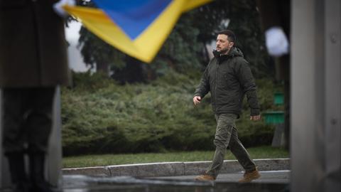 Der ukrainische Präsident Wolodymyr Selenskyj läuft an einer Landes-Flagge vorbei.