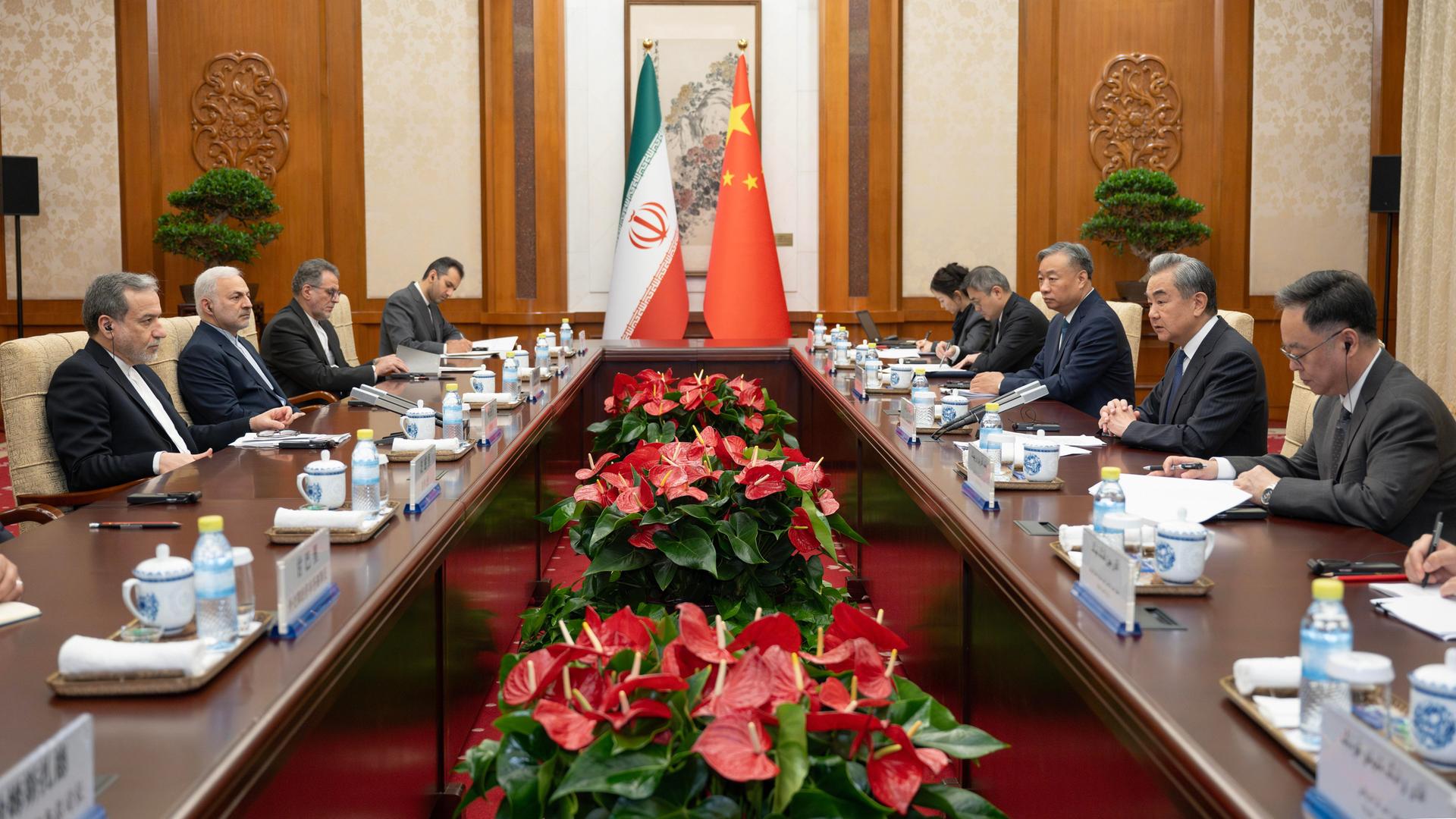 China, Peking: Der chinesische Außenminister Wang Yi und mit sein iranischer Amtskollege Abbas Araghtschi sitzen mit mehreren Personen zusammen. 