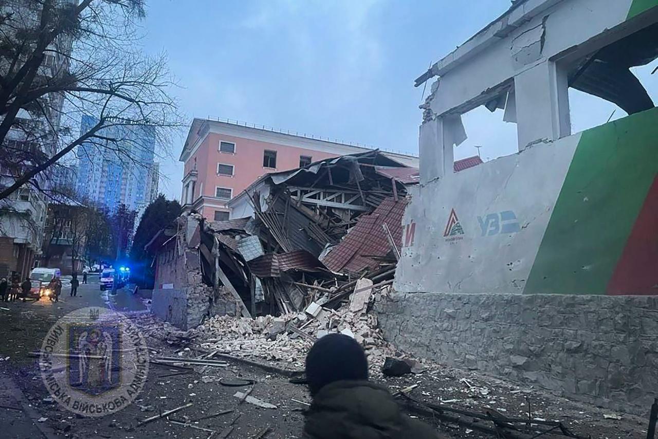 Ukraine, Kiew: Durch russische Angriffe sind mehrere Gebäude zerstört. Schutt liegt auf der Straße. Im Vordergrund eine Person. 