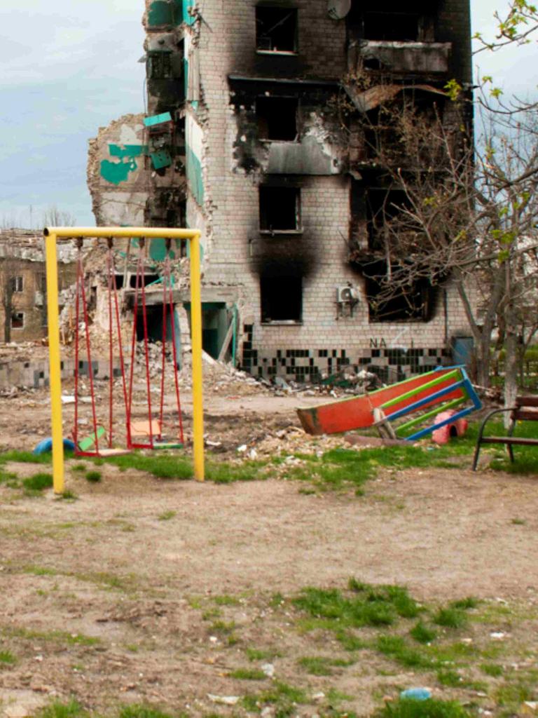 Ein bunter Spielplatz vor ausgebrannten Häuserruinen in der Ukraine Ein bunter Spielplatz vor ausgebrannten Häuserruinen in der Ukraine