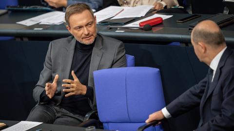 Die beiden sitzen einander zugewandt auf der Regierungsbank und reden miteinander. Lindner spricht und gestikuliert mit beiden Händen. Scholz hört ihm zu. 