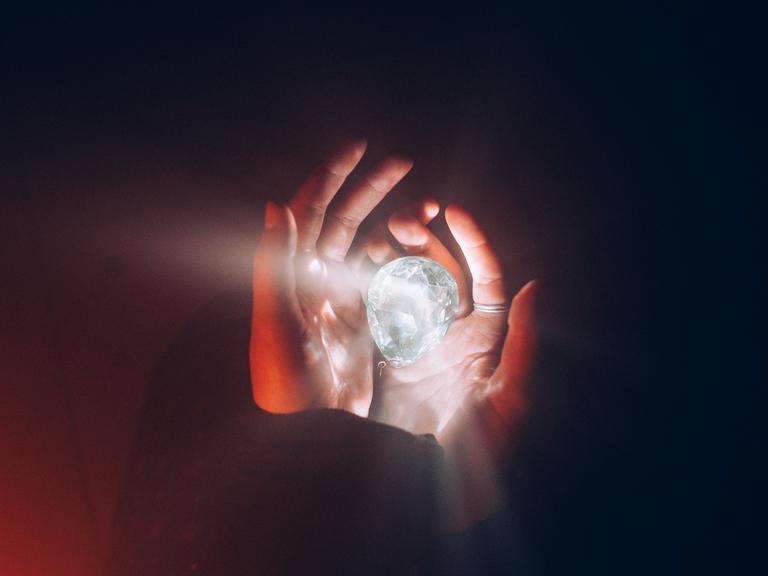 CLOSE-UP OF HUMAN HAND HOLDING ILLUMINATED LIGHT