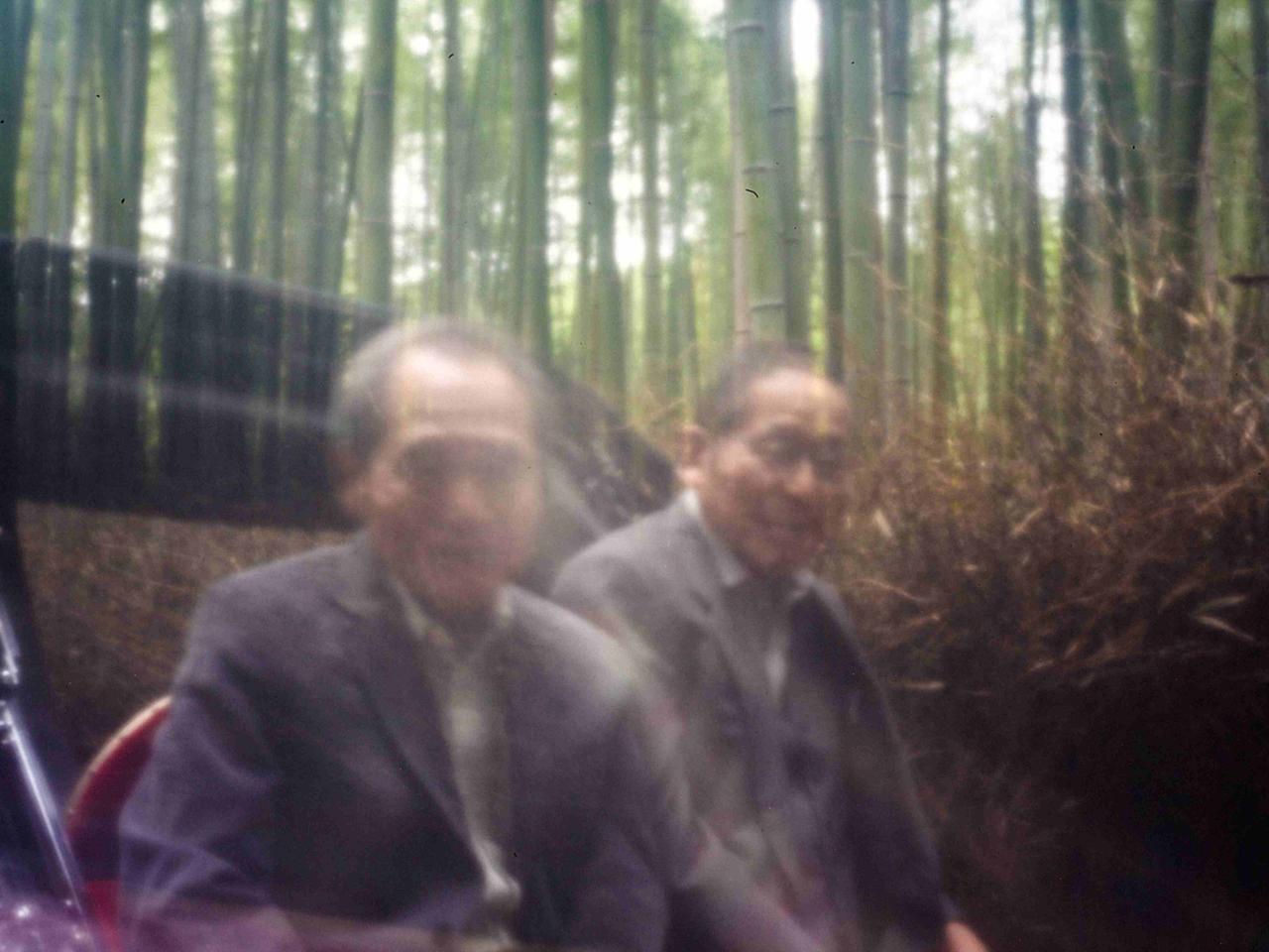 Fotografie mit Pinhole-Technik: Zwei verschwommene, verschwindende Männer in Anzügen in einem Bambuswald in Japan. Fotografie mit Pinhole-Technik: Zwei verschwommene, verschwindende Männer in Anzügen in einem Bambuswald in Japan.