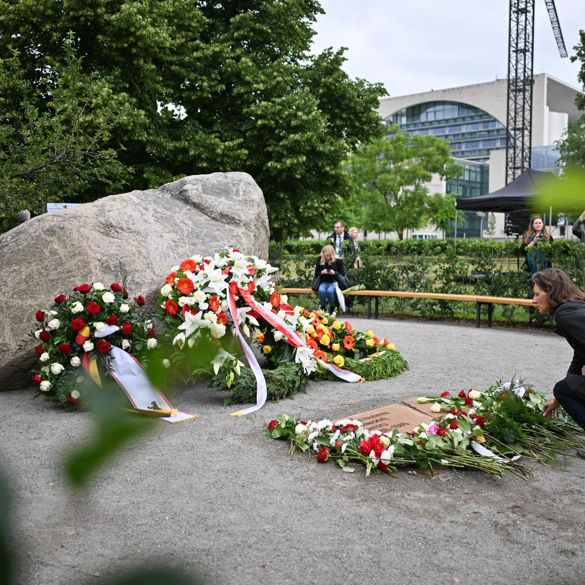 Eine Frau legt während der Übergabe eines temporären Denkmals zur Erinnerung an die polnischen Opfer des Zweiten Weltkriegs und der deutschen Gewaltherrschaft in Berlin eine Blume ab. 