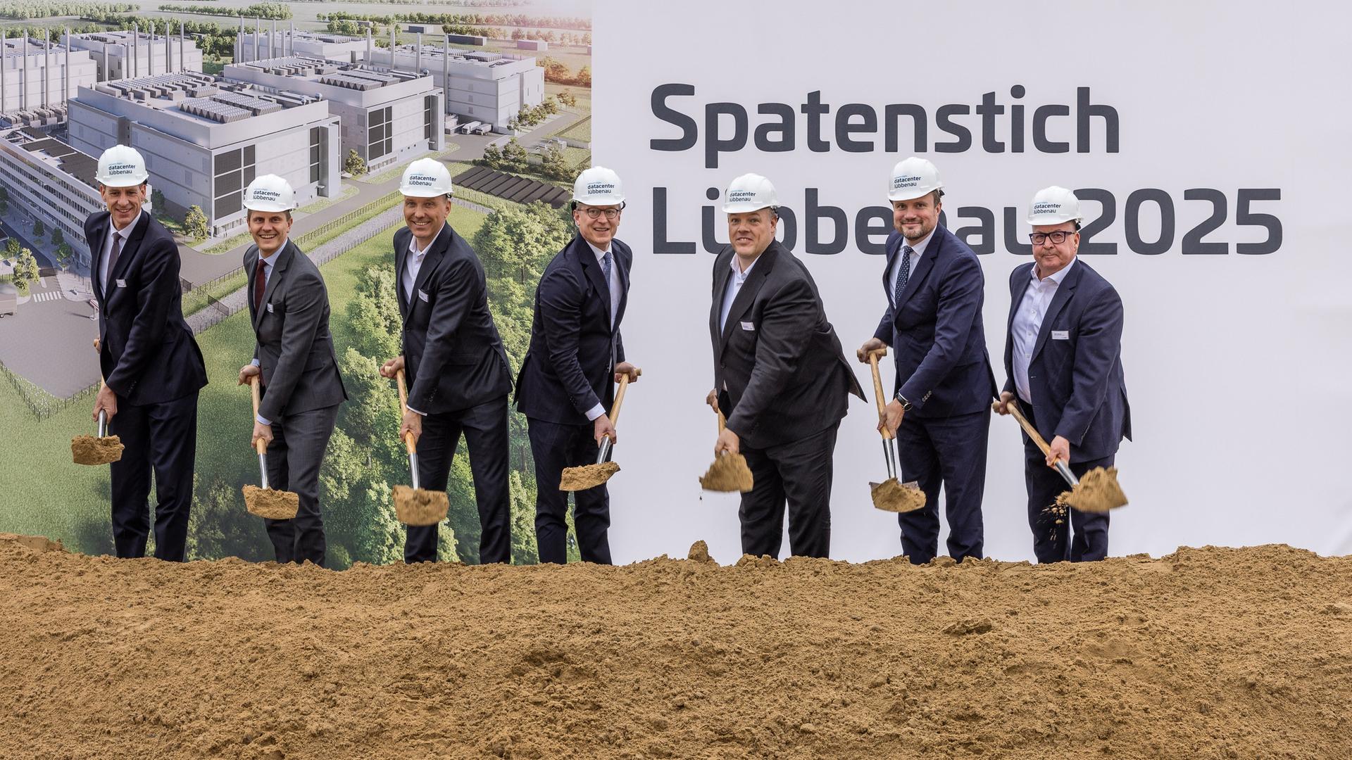 Spatenstich für das Rechenzentrum in Lübbenau. Männer im dunklen Anzug mit Helm auf dem Kopf und Schaufel in der Hand vor einem Schild "Spatenstich Lübbenau" Spatenstich für das Rechenzentrum in Lübbenau. Männer im dunklen Anzug mit Helm auf dem Kopf und Schaufel in der Hand vor einem Schild "Spatenstich Lübbenau"