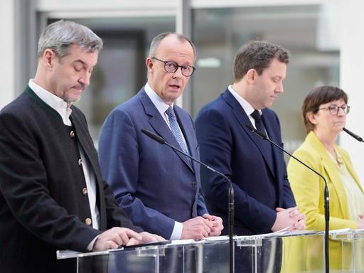 Die Parteivorsitzenden Söder (CSU), Merz (CDU), Klingbeil und Esken (beide SPD) stehen nebeneinander an Rednerpulten. Merz schaut Richtung Kamera, die anderen geradeaus. 