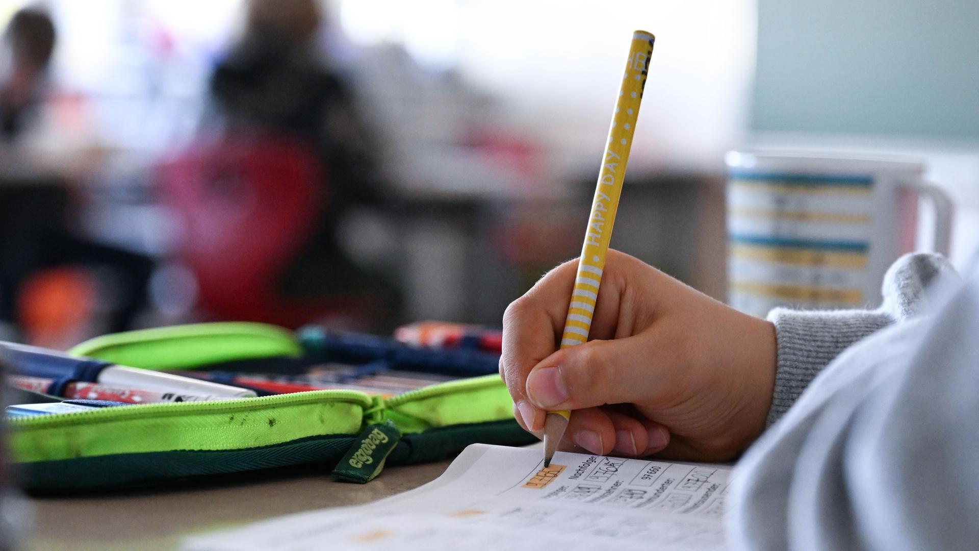 Schüler hält einen Bleistift in der Hand und arbeitet in einem Heft an Mathematikaufgaben