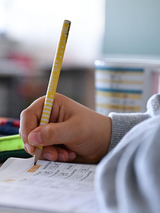 Schüler hält einen Bleistift in der Hand und arbeitet in einem Heft an Mathematikaufgaben