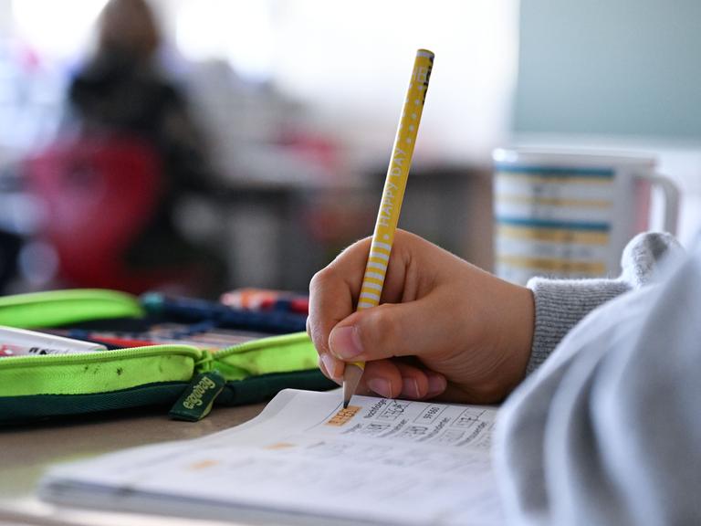 Schüler hält einen Bleistift in der Hand und arbeitet in einem Heft an Mathematikaufgaben