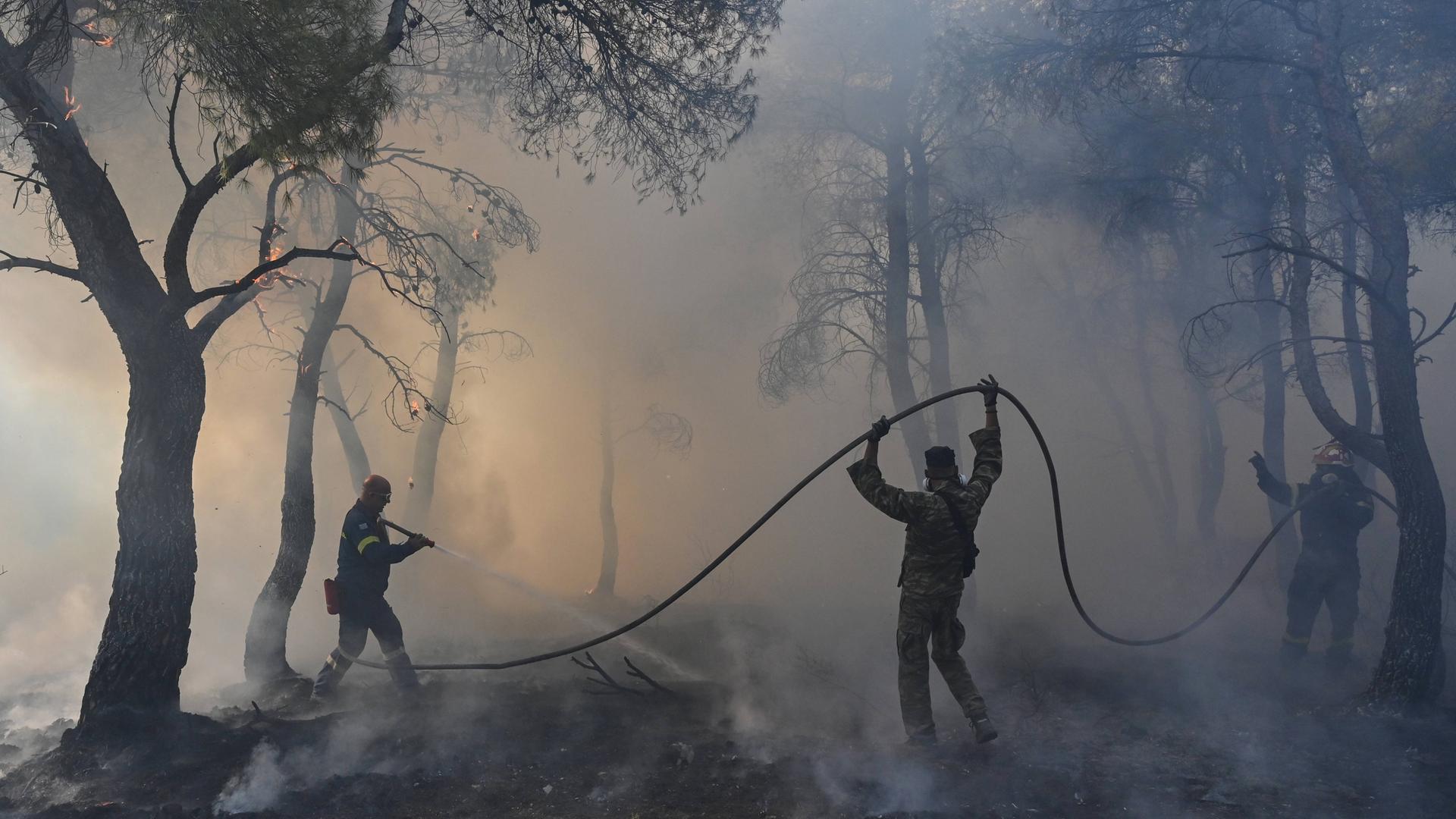 Feuerwehrleute versuchen einen Waldbrand zu löschen am Berg Parnitha bei Athen, Griechenland, 2023.