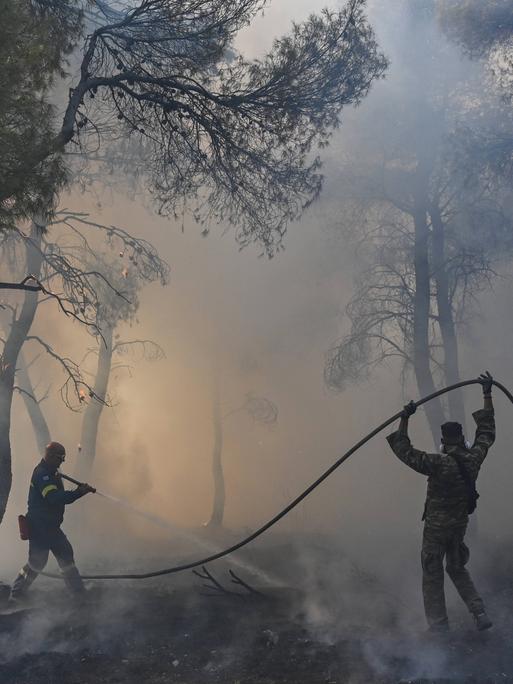 Feuerwehrleute versuchen einen Waldbrand zu löschen am Berg Parnitha bei Athen, Griechenland, 2023.