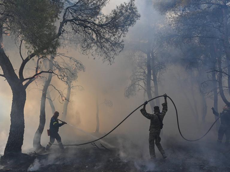 Feuerwehrleute versuchen einen Waldbrand zu löschen am Berg Parnitha bei Athen, Griechenland, 2023.