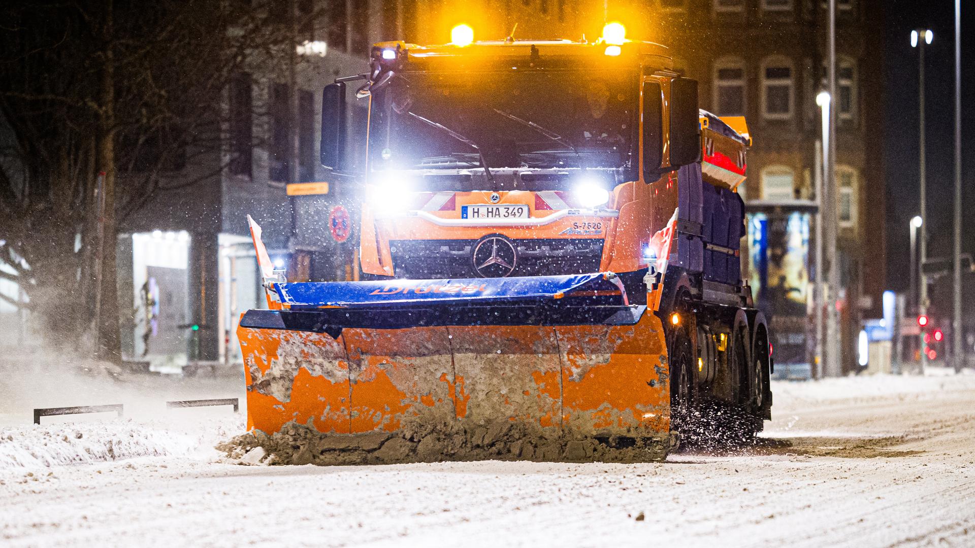 Ein Räumfahrzeug ist am frühen Morgen auf einer verschneiten Straße im Zentrum von Hannover im Einsatz.
