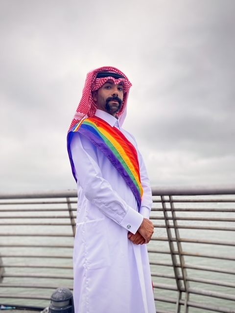 Nas Mohamedin traditionellem katarischem gewand mit einer Regenbogenschärpe.