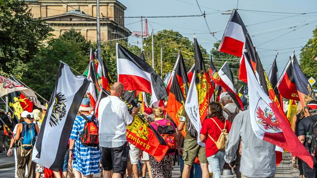 Reichsbürger-Treffen, Demonstrationszug, rot-weiße Flaggen.