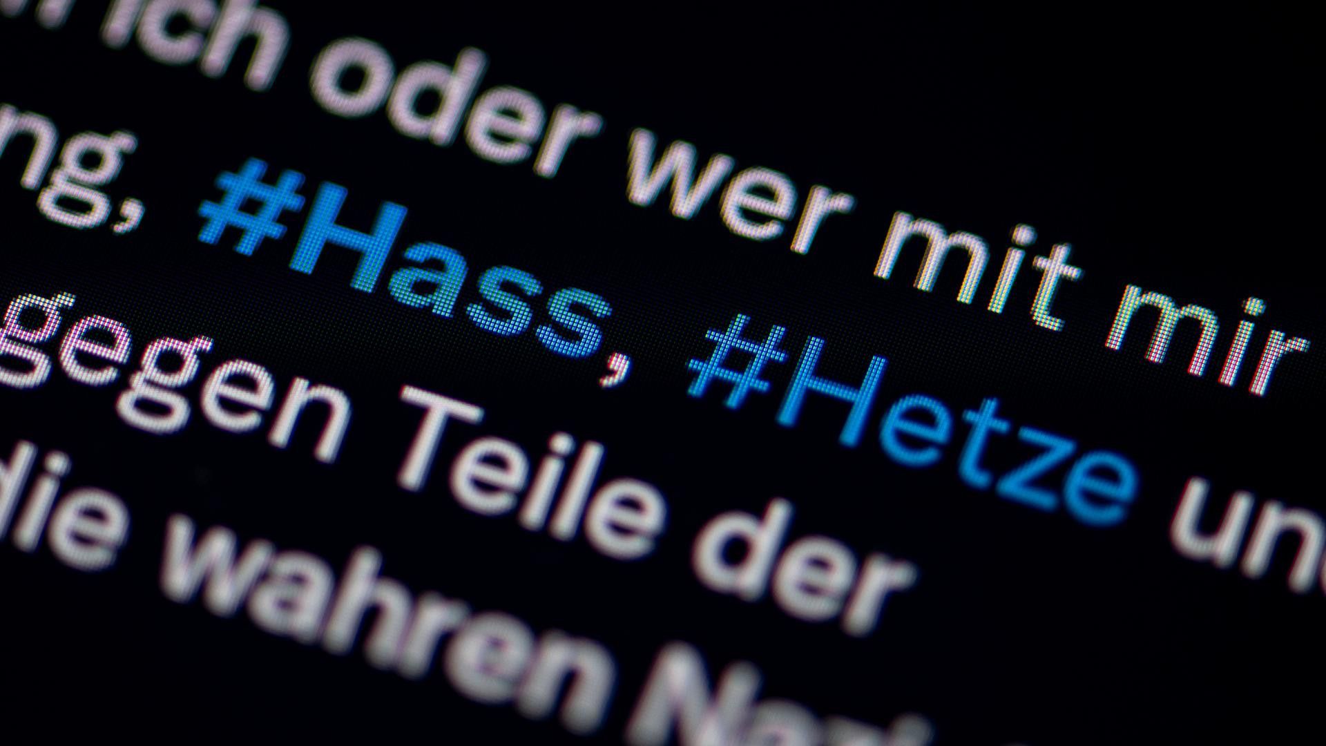 Auf dem Bildschirm eines Smartphones sieht man die Hashtags Hass und Hetze in einem Twitter-Post