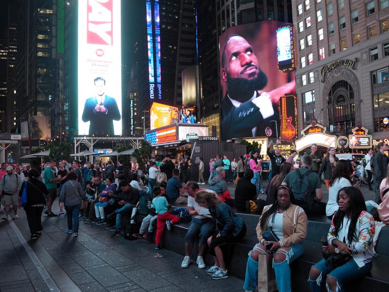 Menschen sitzen am New Yorker Times Square, 27.09.2024