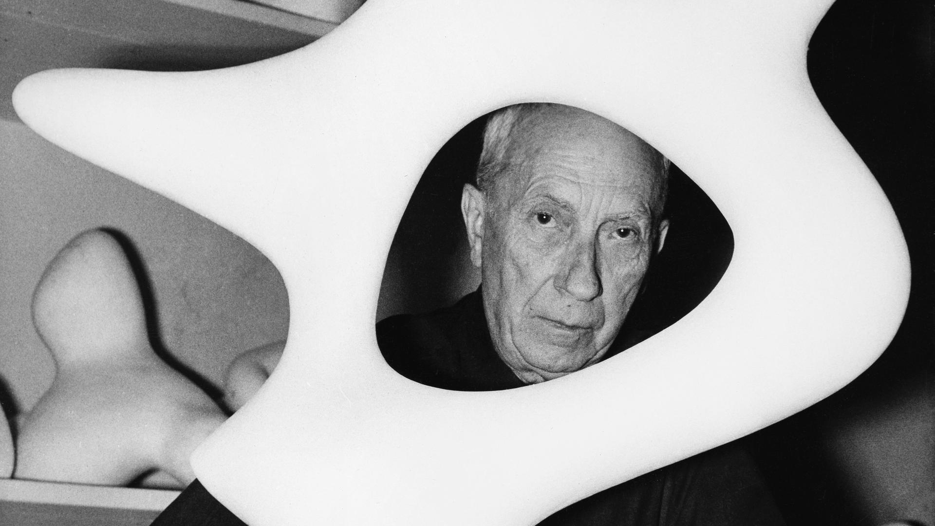 Der Maler, Bildhauer und Lyriker Hans Arp (1886-1966) schaut in seinem Atelier durch eine seiner Plastiken. Der Maler, Bildhauer und Lyriker Hans Arp (1886-1966) schaut in seinem Atelier durch eine seiner Plastiken.