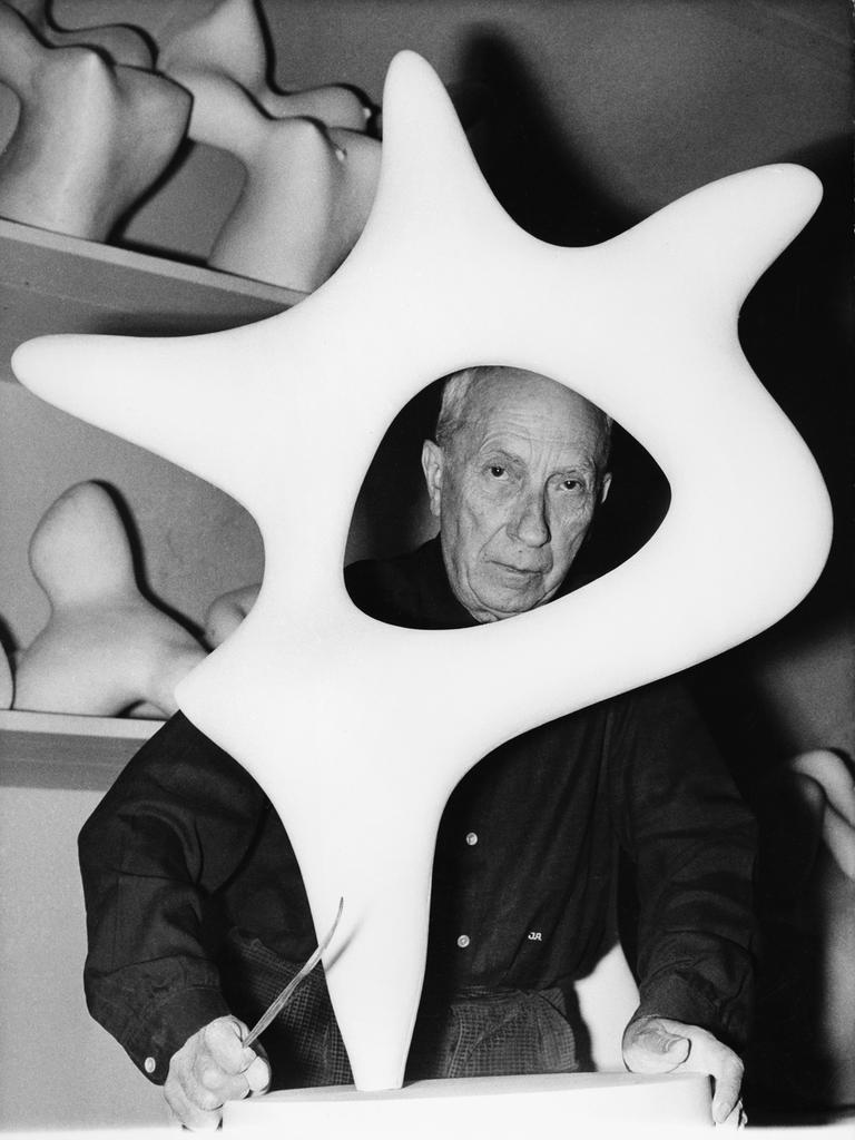Der Maler, Bildhauer und Lyriker Hans Arp (1886-1966) schaut in seinem Atelier durch eine seiner Plastiken. 