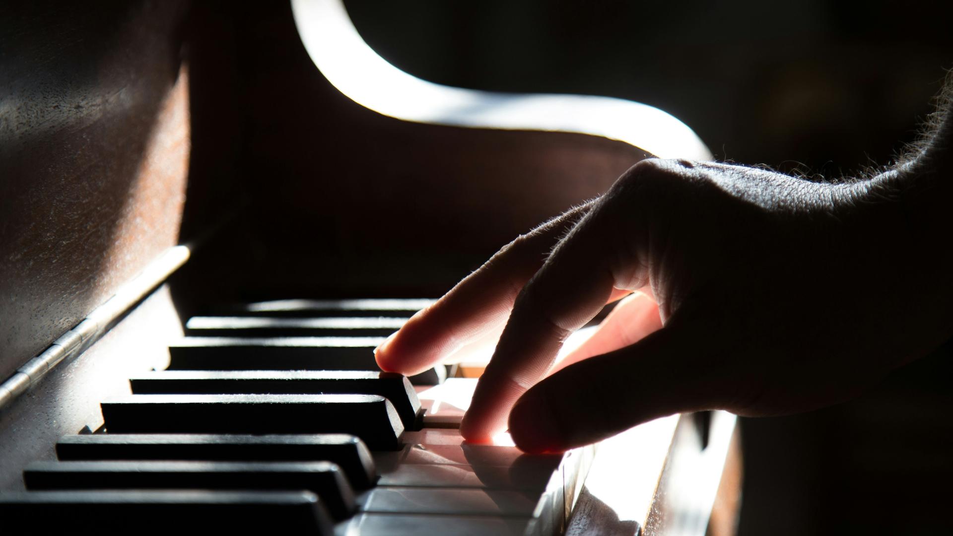 Eine rechte Hand schlägt Klaviertasten im Diskant an Eine rechte Hand schlägt Klaviertasten im Diskant an