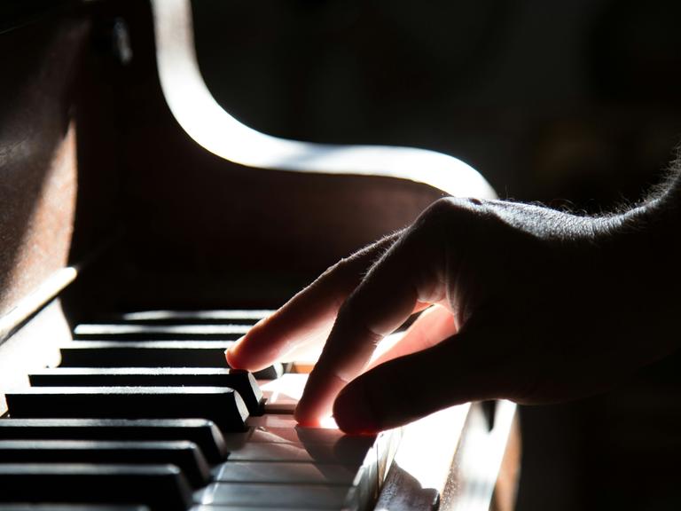 Eine rechte Hand schlägt Klaviertasten im Diskant an
