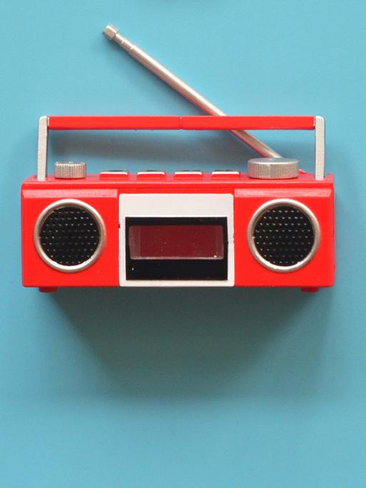 Ein rotes radio aus den 1970er Jahren vor blauem Hintergrund. 