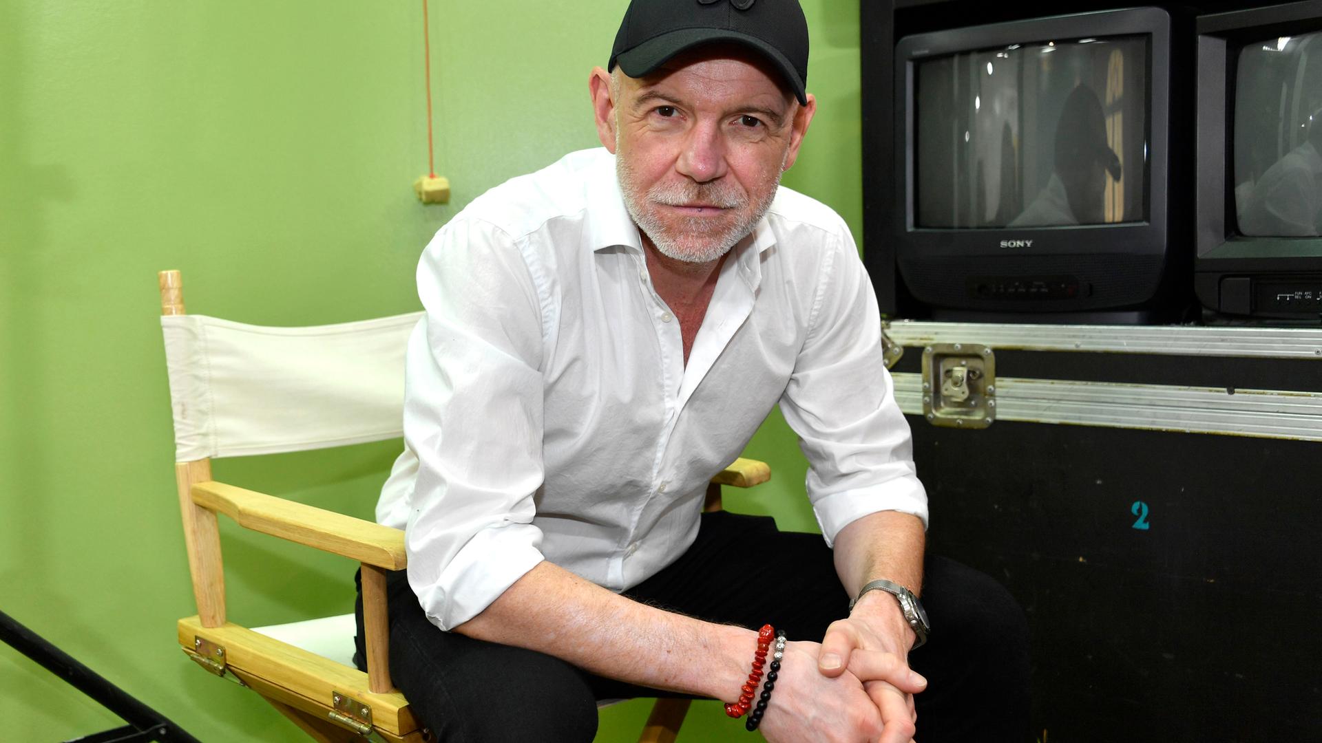 Dietmar Wunder sitzt in einem Studio im Filmpark Babelsberg auf einem Regiestuhl und schaut freundlich in die Kamera Dietmar Wunder sitzt in einem Studio im Filmpark Babelsberg auf einem Regiestuhl und schaut freundlich in die Kamera