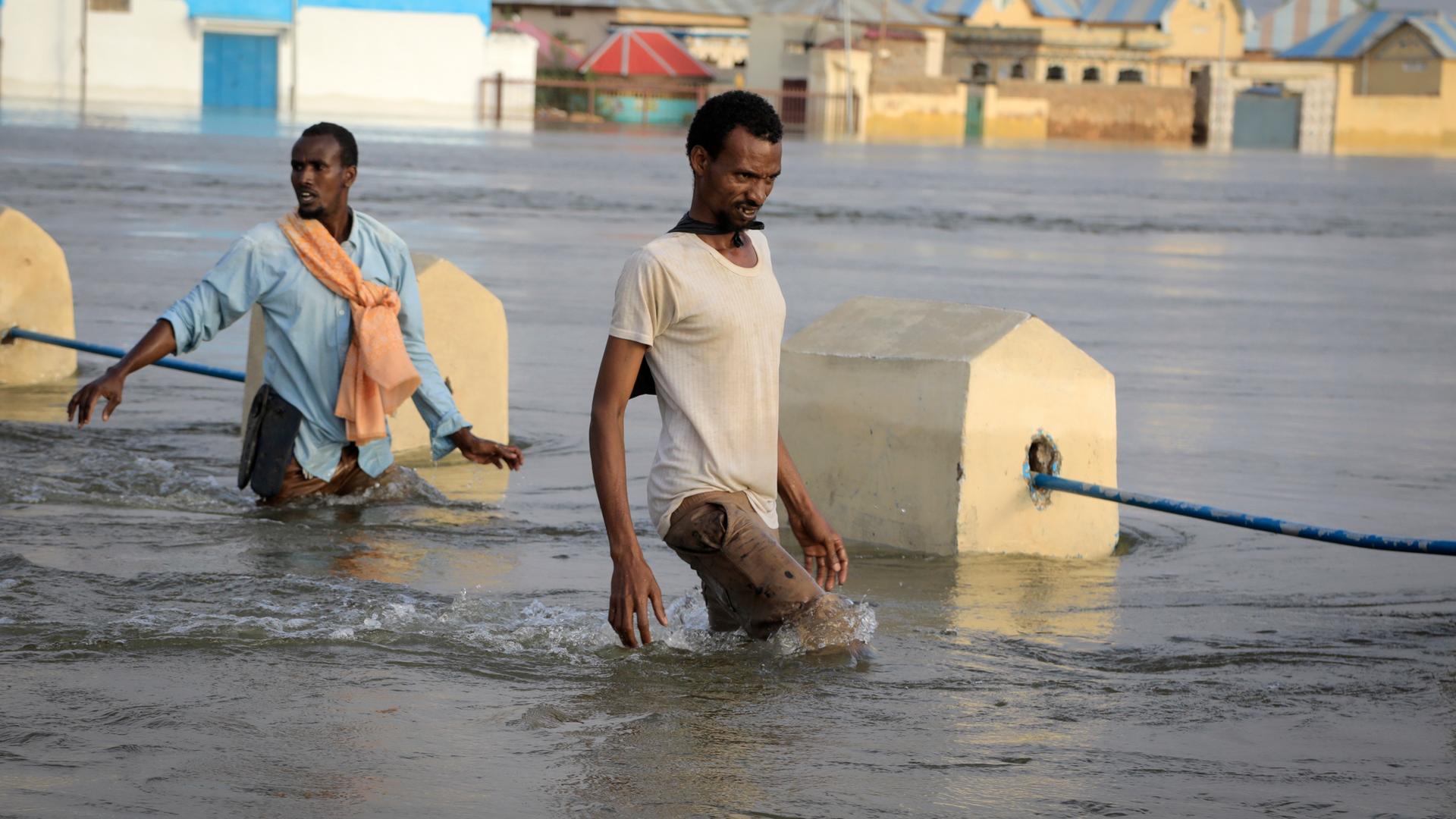 Zwei Männer waten durch Hochwasser.