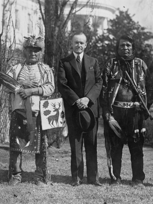 Historisches Schwarzweißfoto von Calvin Coolidge mit Native Americans der Osage Nations vor dem Weißen Haus.