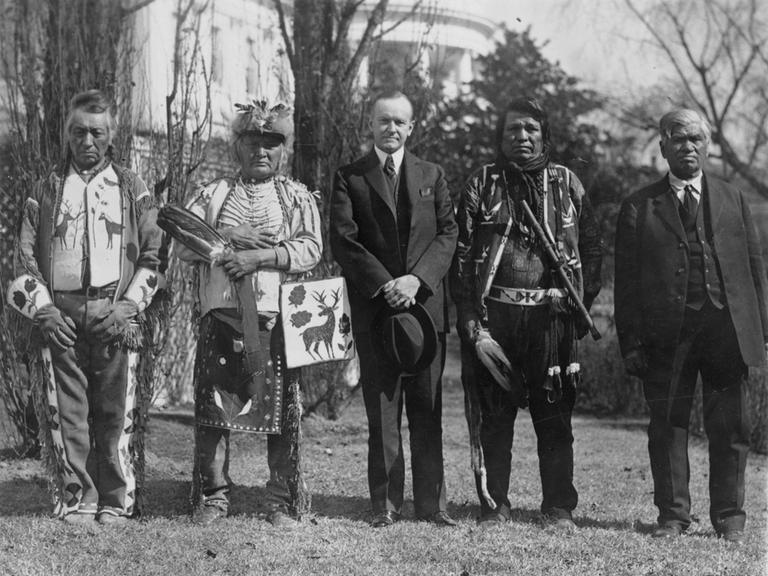 Historisches Schwarzweißfoto von Calvin Coolidge mit Native Americans der Osage Nations vor dem Weißen Haus.