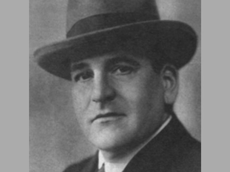 Hugo Bettauer im Anzug und mit Hut. Eine schwarz-weiß Fotografie.