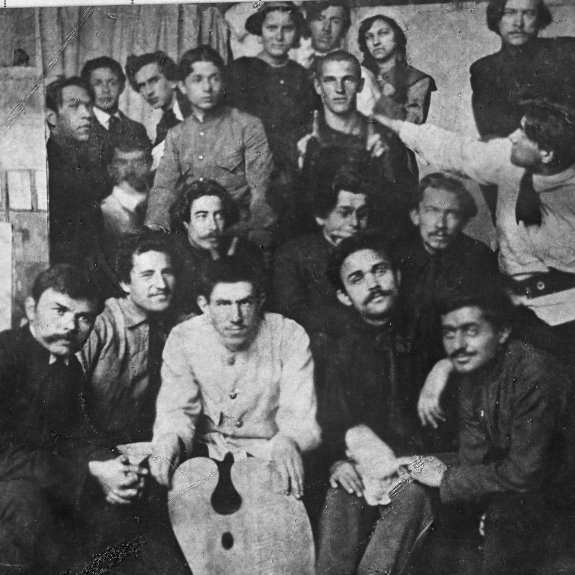 Wladimir Wladimirowitsch Majakowski sitzt umringt von Kollegen und posiert für ein Gruppenfoto.