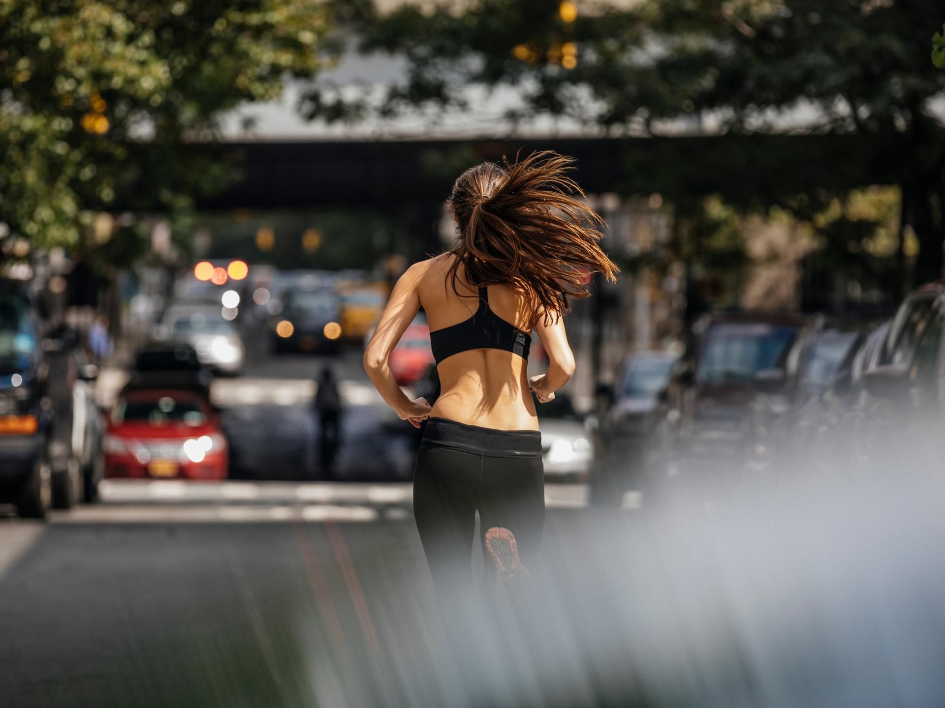 Eine junge Frau ist beim Joggen in einer Stadt von hinten zu sehen