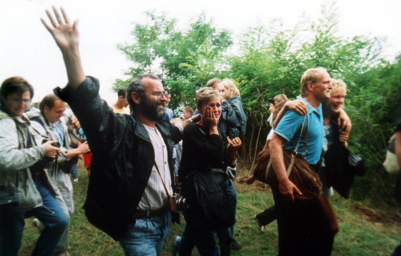 Das Archivbild zeigt jubelnde DDR-Flüchtlinge, die am 19.08.1989 Österreich erreichen. Etwa 600 DDR-Bürger nutzten ein paneuropäisches Picknick an der ungarisch-österreichischen Grenze in Sopron, Ungarn, bei dem ein Grenztor geöffnet wurde, zur Flucht in den Westen. Diese erste Massenflucht war der Anfang vom Ende für die DDR mit dem Fall der Berliner Mauer am 9. November 1989. dpa (zu dpa Serie 25 Jahre Mauerfall - "Das Paneuropäische Picknick im ungarischen Sopron am 19.08.1989") ++