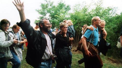 Das Archivbild zeigt jubelnde DDR-Flüchtlinge, die am 19.08.1989 Österreich erreichen. Etwa 600 DDR-Bürger nutzten ein paneuropäisches Picknick an der ungarisch-österreichischen Grenze in Sopron, Ungarn, bei dem ein Grenztor geöffnet wurde, zur Flucht in den Westen. Diese erste Massenflucht war der Anfang vom Ende für die DDR mit dem Fall der Berliner Mauer am 9. November 1989. dpa (zu dpa Serie 25 Jahre Mauerfall - "Das Paneuropäische Picknick im ungarischen Sopron am 19.08.1989") ++