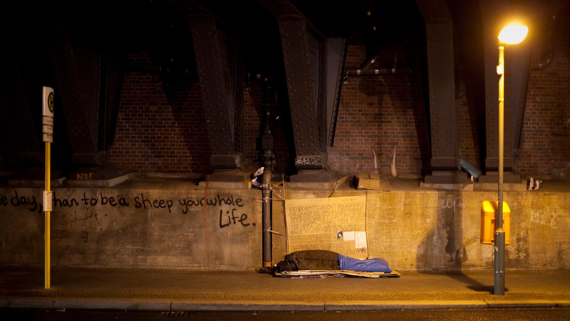 Ein Obdachloser schläft unter einer Brücke in Berlin.